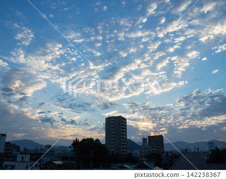 Cityscape with clouds and blue sky illuminated by the morning sun. Tags 142238367