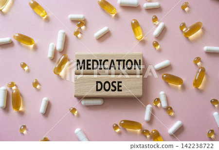 Medication dose symbol. Concept word Medication dose on wooden blocks. Beautiful pink background with pills. Medicine and Medication dose. Copy space Medication dose symbol. Concept word Medication dose on wooden blocks. Beautiful pink background with pills. Medicine and Medication dose. Copy space 142238722