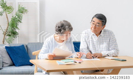 Senior couple filling out paperwork for end-of-life planning. Senior couple filling out paperwork for end-of-life planning. 142239183