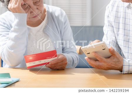Senior couple contemplate while looking at their bankbook. Senior couple contemplate while looking at their bankbook. 142239194