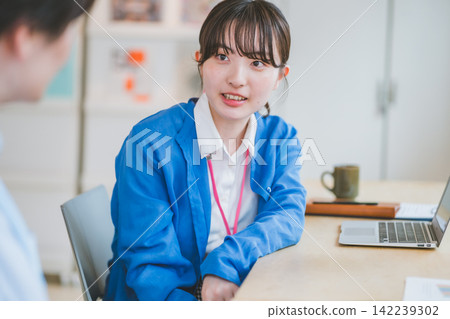 非正式交流：一位配戴員工證的女士正在與同事聊天。 142239302