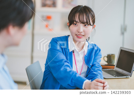 商務場景:一名配戴員工證的女子正在與同事交談。 商務場景:一名配戴員工證的女子正在與同事交談。 142239303