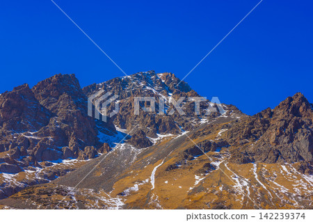 Rugged Mountain Range Under Clear Blue Sky in Kyrgyzstan 142239374