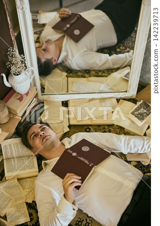 Immersed in personal reflection surrounded by books and soothing light Immersed in personal reflection surrounded by books and soothing light 142239713