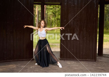 Female engaging in vigorous dance workout amidst nature setting Female engaging in vigorous dance workout amidst nature setting 142239744