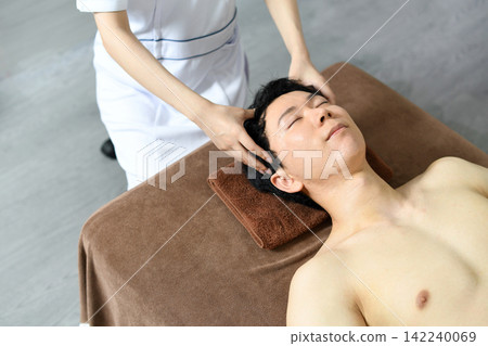 一位年輕的亞洲男子正在享受頭部水療。 一位年輕的亞洲男子正在享受頭部水療。 142240069
