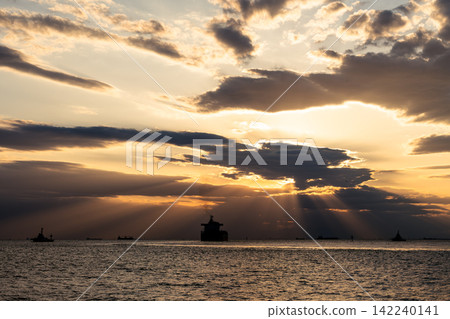 The silhouette of a ship floating on the sea and rays of light shining through the clouds The silhouette of a ship floating on the sea and rays of light shining through the clouds 142240141