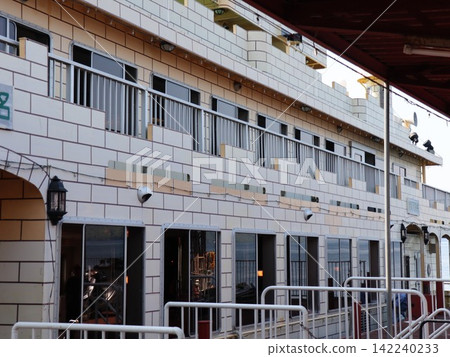 A close-up view of the lake cruise boat's hull, with its white exterior walls and rows of windows on the deck. A close-up view of the lake cruise boat's hull, with its white exterior walls and rows of windows on the deck. 142240233