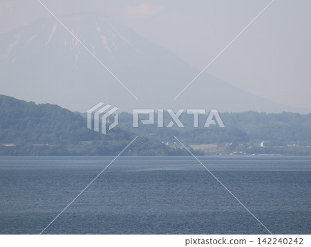 一座巍峨的山峰聳立在薄霧之中,平靜的湖面波光粼粼──這是一幅沐浴在逆光下的夏日景象。 一座巍峨的山峰聳立在薄霧之中,平靜的湖面波光粼粼──這是一幅沐浴在逆光下的夏日景象。 142240242