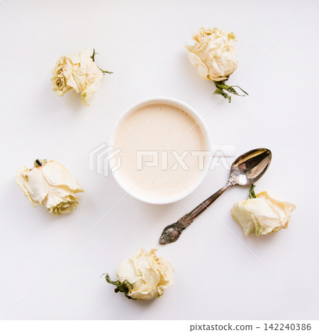 Still life of a cup of coffee or cappuccino with dry white roses around. Square. Still life of a cup of coffee or cappuccino with dry white roses around. Square. 142240386