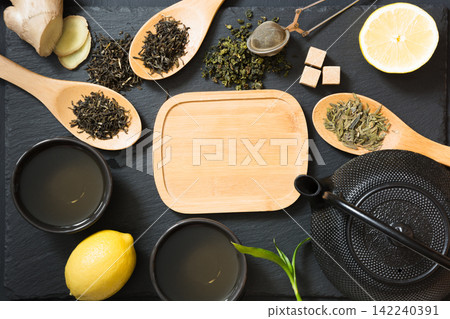 Green japanese and chinese tea with traditional food set on black table. Top view with copy space. Green japanese and chinese tea with traditional food set on black table. Top view with copy space. 142240391