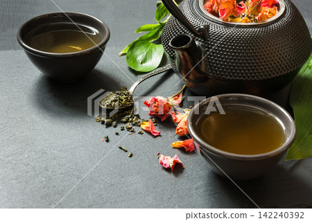 Green tea with rose flower on black slate dish. Close up with copy space. Green tea with rose flower on black slate dish. Close up with copy space. 142240392
