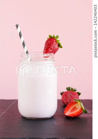 Strawberry milkshake with berry in mason jar on pink. Close up. Summer drink. 142240403