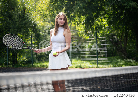 Female tennis player with racket and ball behind net Female tennis player with racket and ball behind net 142240436