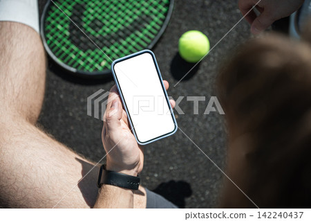 Tennis player using smartphone on court with blank screen Tennis player using smartphone on court with blank screen 142240437