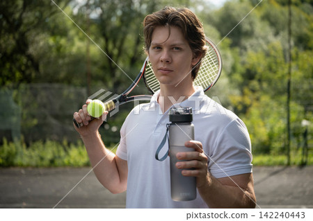 Tennis player holding water bottle after outdoor workout Tennis player holding water bottle after outdoor workout 142240443