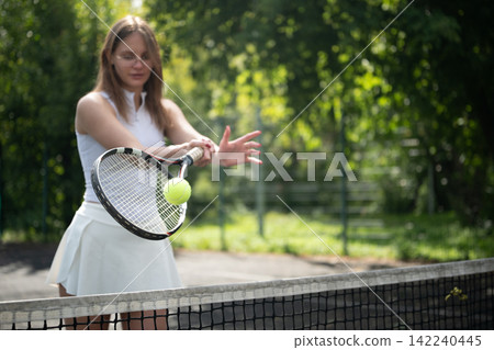 Female tennis player hitting ball during outdoor match Female tennis player hitting ball during outdoor match 142240445