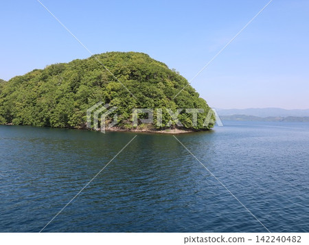 一座鬱鬱蔥蔥的小島漂浮在平靜的夏日湖面上。 142240482