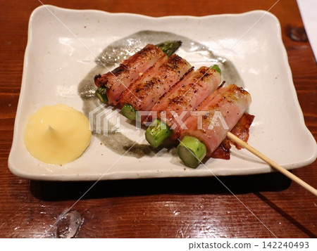 Bacon-wrapped asparagus skewers, served with mayonnaise. Bacon-wrapped asparagus skewers, served with mayonnaise. 142240493