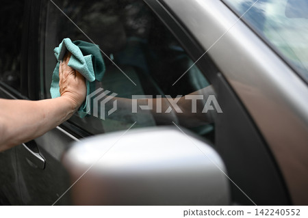 Cleaning car window with microfiber cloth by hand Cleaning car window with microfiber cloth by hand 142240552