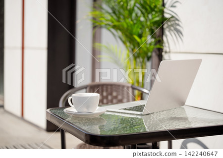 Laptop and coffee on outdoor cafe table for remote work Laptop and coffee on outdoor cafe table for remote work 142240647