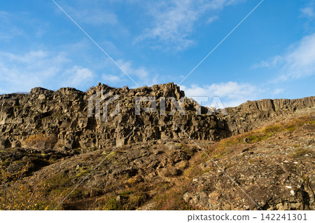 Rocky tectonic Almannagja mountain. Mountain geology rock. Geology rocky cliff. Cliff edge Almannagja. Mountain wall cliff in Iceland. Geological tectonic rock in nature of Iceland 142241301