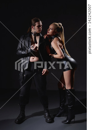 Provocative couple in black leather fashion with chains on dark background Provocative couple in black leather fashion with chains on dark background 142242007