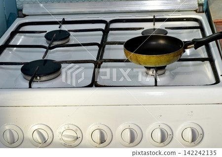 The frying pan is on the gas stove. The frying pan is on the gas stove. 142242135