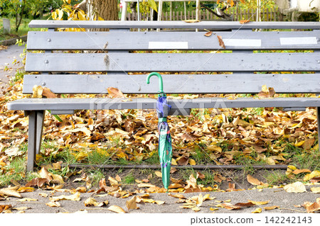 Autumn. An umbrella stands near a bench. Autumn. An umbrella stands near a bench. 142242143