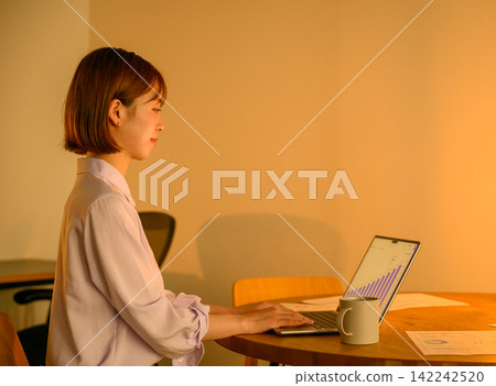 A businesswoman working on her laptop in the office at night. 142242520