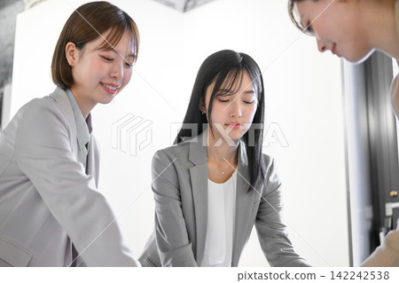 Teamwork among female employees during a meeting in the office Teamwork among female employees during a meeting in the office 142242538