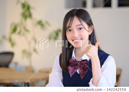 一名正在考試的高中女生豎起大拇指,露出微笑。 一名正在考試的高中女生豎起大拇指,露出微笑。 142242559