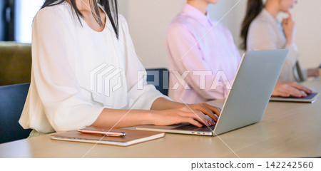 辦公室裡女員工使用筆記型電腦的場景。 142242560