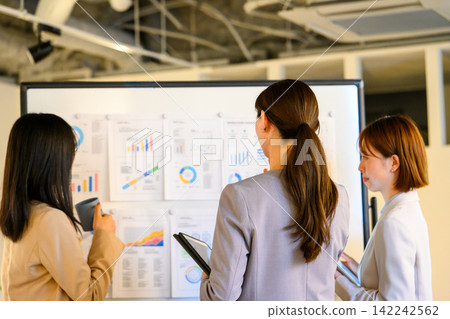 Three women discussing on a whiteboard. Three women discussing on a whiteboard. 142242562