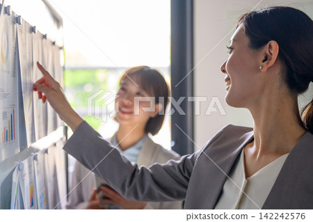 一位女士指著白板上的圖表。 一位女士指著白板上的圖表。 142242576