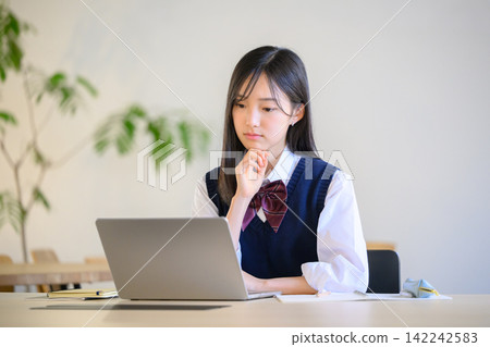 A high school girl studying on her laptop. A high school girl studying on her laptop. 142242583