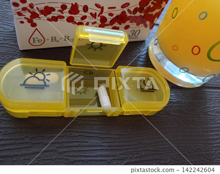 A container with an open compartment and an iron supplement capsule A container with an open compartment and an iron supplement capsule 142242604