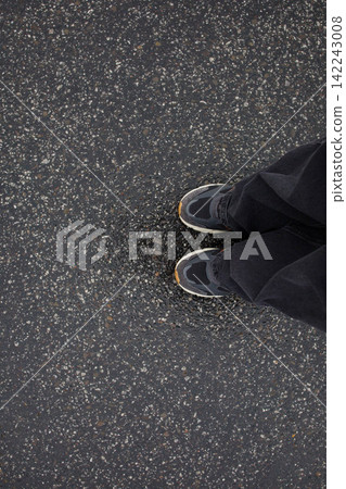 Feet of woman in sneakers and loose grey jeans standing on wet asphalt after the rain close up top view. Human in the city, walk in rainy weather, minimalistic background Feet of woman in sneakers and loose grey jeans standing on wet asphalt after the rain close up top view. Human in the city, walk in rainy weather, minimalistic background 142243008