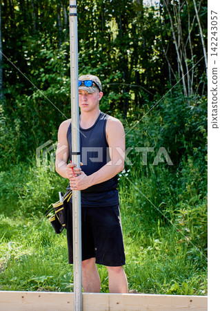 Surveying rod is held upright by field technician during precise site measurements for construction layout and elevation assessment tasks. Surveying rod is held upright by field technician during precise site measurements for construction layout and elevation assessment tasks. 142243057