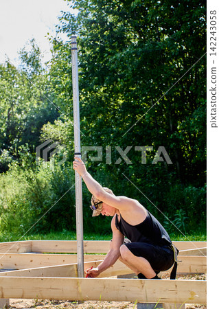 Measurement pole stands vertically in surveyor hands during professional fieldwork focused on elevation checks and precise building layout. Measurement pole stands vertically in surveyor hands during professional fieldwork focused on elevation checks and precise building layout. 142243058