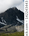 Rugged Mountain Peak with Snow and Clouds 142243443