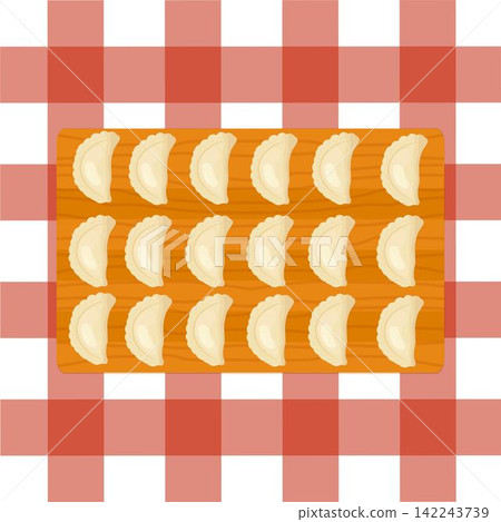Dumplings on a wooden cutting board on red checkered tablecloth 142243739