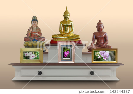 front view traditional multi-tiered wooden altar table featuring three religious statues and three framed floral pictures on cream and brown background, copy space 142244387