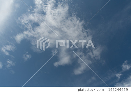 Soft, white cirrus clouds spread across a clear blue sky. Soft, white cirrus clouds spread across a clear blue sky. 142244459