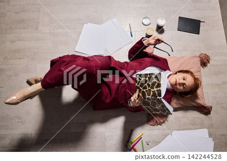 Artist relaxing amidst scattered supplies during creative downtime 142244528