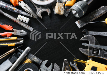 Assorted hand tools arranged around open center on black background Assorted hand tools arranged around open center on black background 142244532