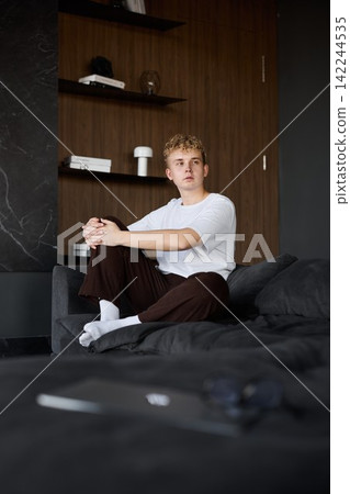 Casual male freelancer with focused look in contemporary living workspace Casual male freelancer with focused look in contemporary living workspace 142244535