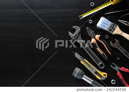 Assorted hand tools arranged on dark wooden surface with large empty copy space Assorted hand tools arranged on dark wooden surface with large empty copy space 142244536