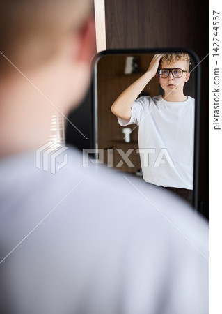 Young caucasian male checking mirror before virtual interview Young caucasian male checking mirror before virtual interview 142244537