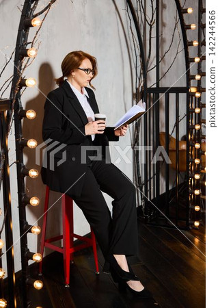 Redhaired woman carefully studies her coffee during branding session Redhaired woman carefully studies her coffee during branding session 142244566